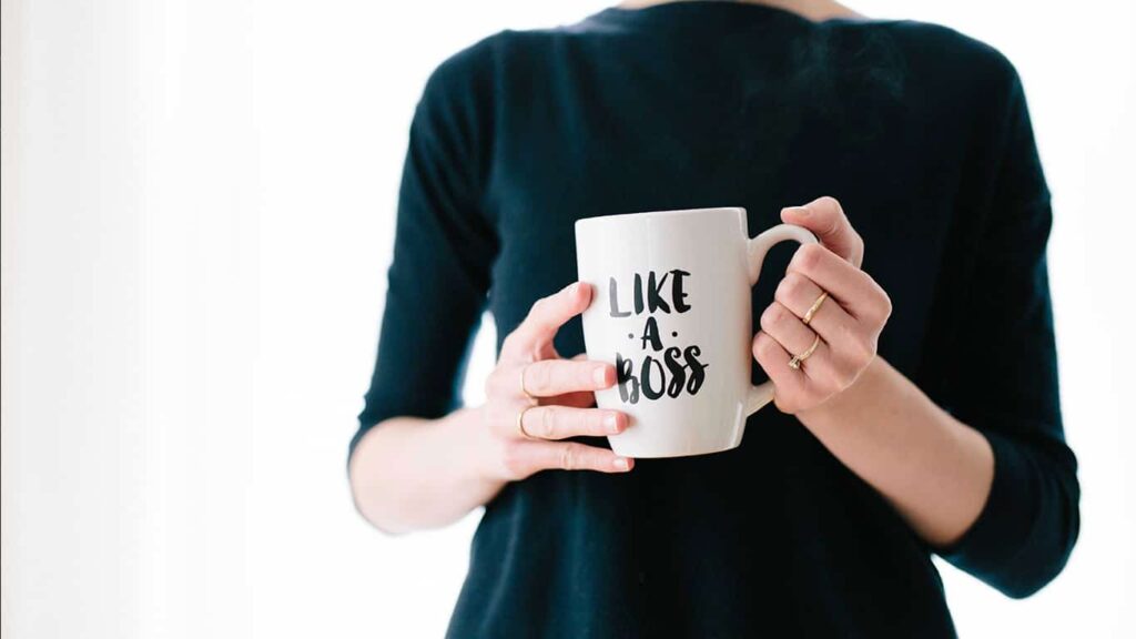 Uma mulher segura uma caneca na altura do busto, escrito “Like a boss”, em tradução livre: como um chefe. Ela representa a melhora na carreira depois das palestras do MBX. 