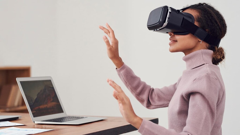 Mulher sentada em uma cadeira vestida de um óculos de realidade virtual que se relaciona ao metaverso - tema de gestão de vendas na nrf esse ano