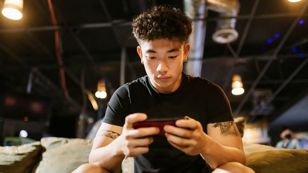 Homem sentado jogando e não fazendo um uso saudável e consciente do celular.