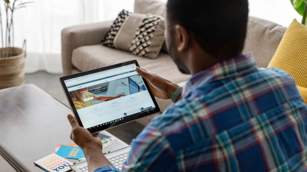 Homem que sabe como utilizar o LinkedIn para crescer profissionalmentesenta e utiliza seu tablet para isso.
