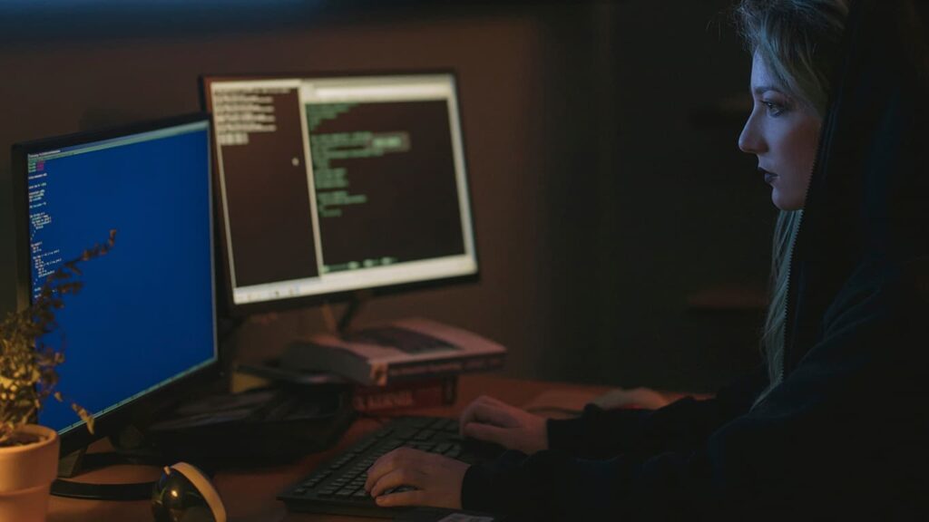 Mulher trabalhando com Engenharia de Dados com dois computadores à frente.