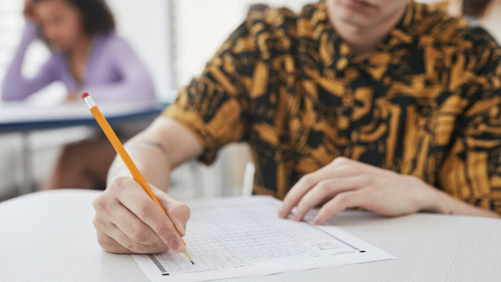 Imagem de uma pessoa segurando um lápis em ambiente escolar para remeter à importância da educação inclusiva.
