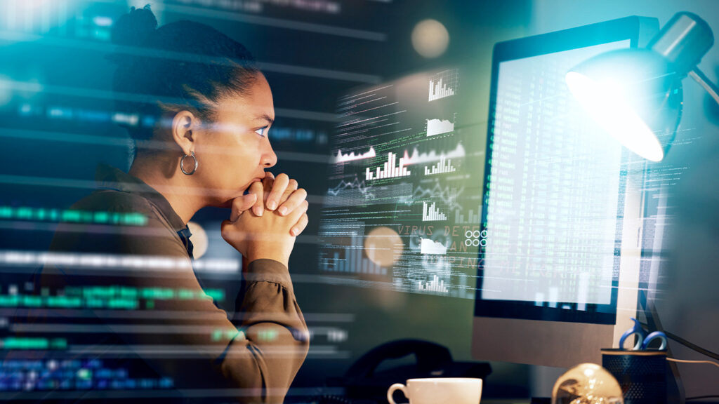 Mulher observa dados no computador em alusão à gestão de finanças e controladoreia.