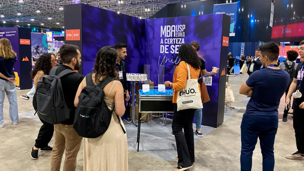 Stand do MBA USP/Esalq no Web Summit Rio com participantes interagindo com a equipe.