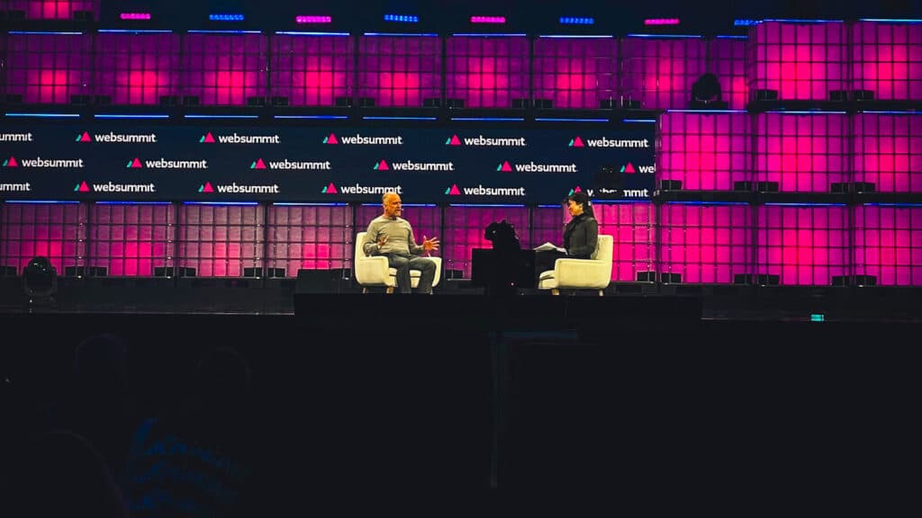 Duas pessoas estão sentadas em um dos palcos do Web Summit.