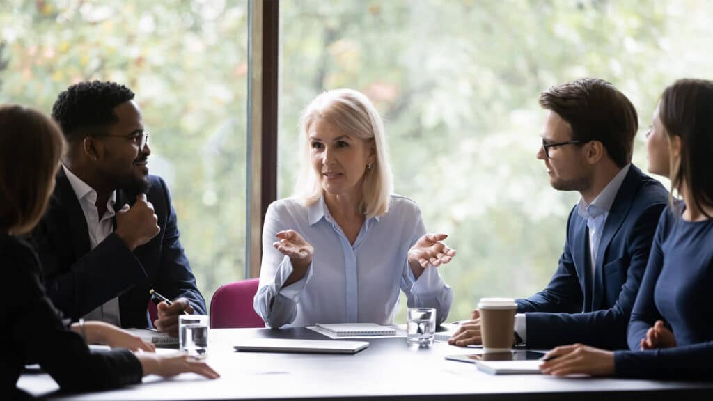 Imagem de pessoas sentadas ao redor de uma mesa em uma reunião, em alusão às perspectivas de CEOs para 2024