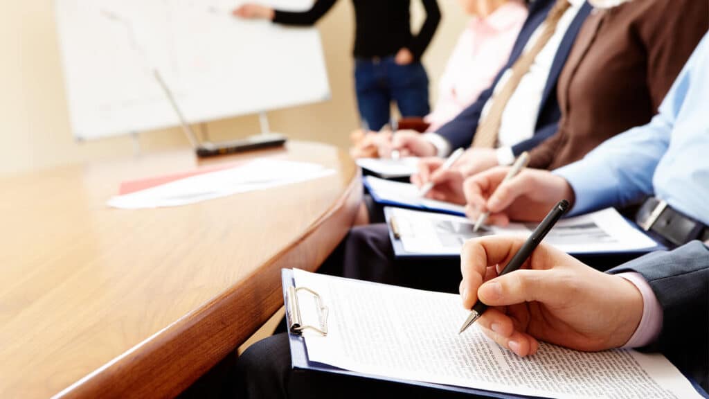 Uma banca avalia o trabalho apresentado por uma pessoa em projeção na parede, em referência ao trabalho desenvolvido a partir do TCC do MBA USP/Esalq que foi premiado em evento científico.