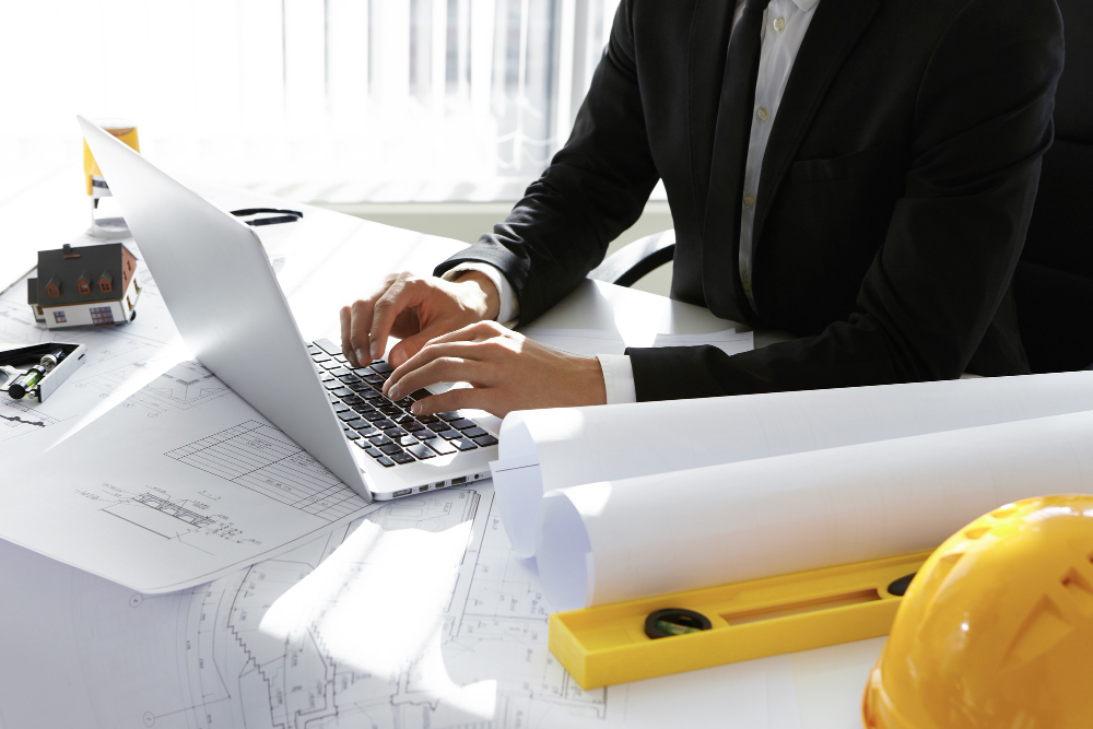 Engenheiro civil analisando projetos e planejamento no notebook, avaliando a necessidade de um MBA para engenheiro civil.