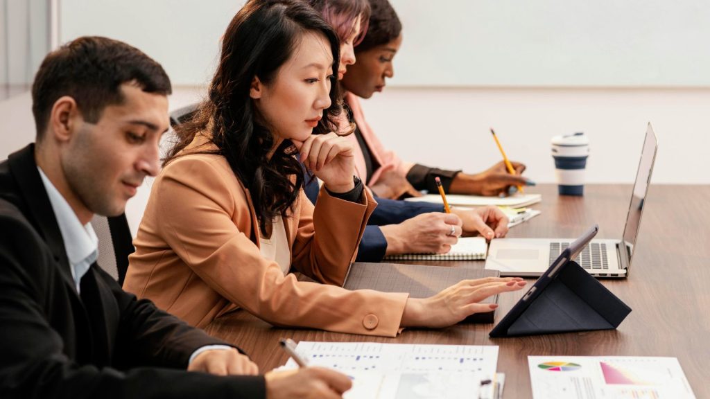 Grupo diverso de profissionais em reunião de trabalho, representando os diferentes perfis de público da educação executiva.